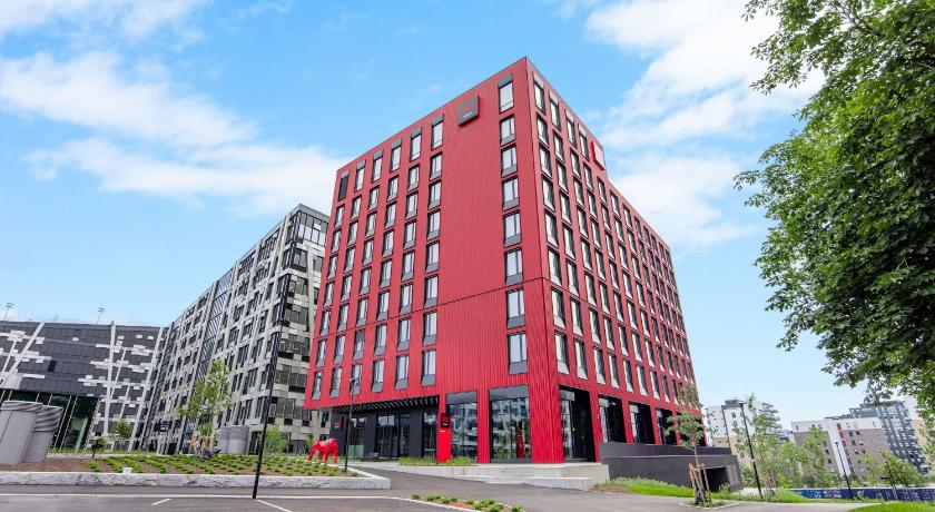 a tall building with a red roof on the side of the street, Radisson RED Oslo Okern in Oslo