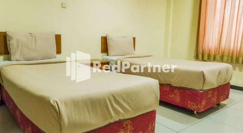 a hotel room with two beds and two nightstands, Grand Kembar Hotel RedPartner in Bandung