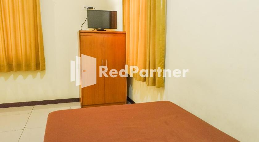 a hotel room with a bed and a television, Grand Kembar Hotel RedPartner in Bandung