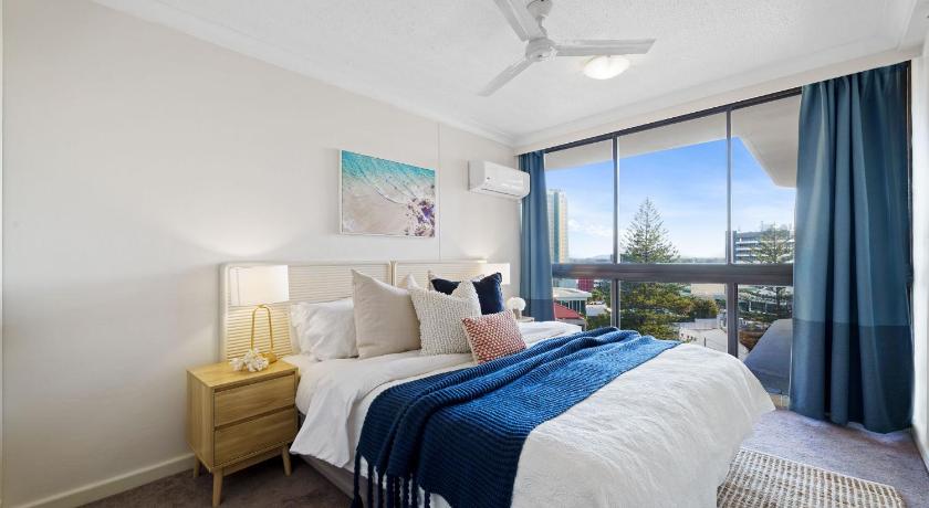 a bedroom with a large bed and a large window, Beachcomber Resort Surfers Paradise in Gold Coast