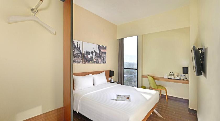 a bedroom with a large bed and a large window, Whiz Prime Hotel Khatib Sulaiman Padang in Padang