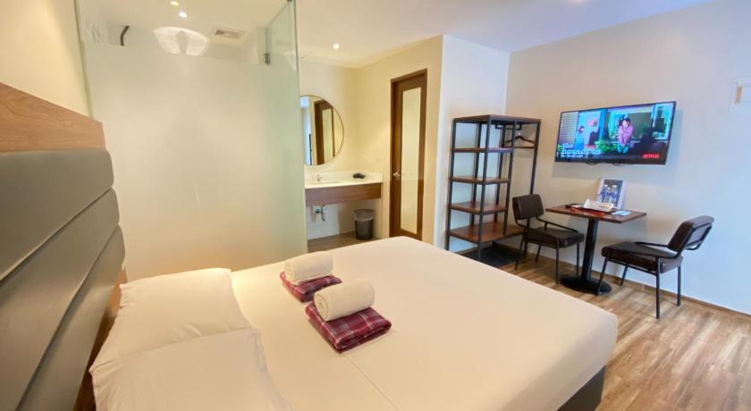 a hotel room with a bed and a tv, The Hub District Garden Suites in Manila