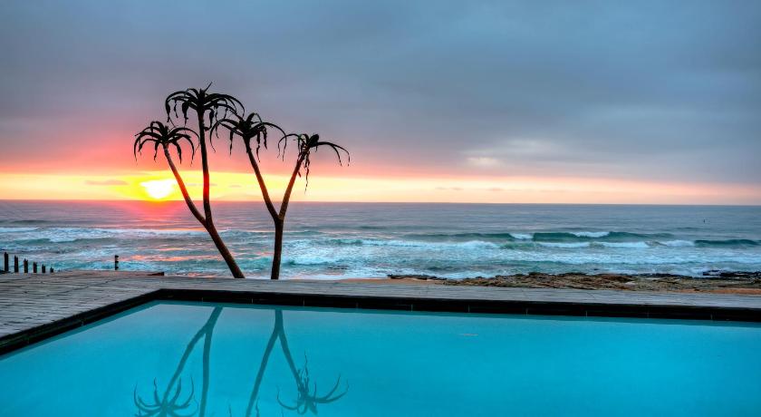 a sunset view of a beach with palm trees, Canelands Beach Club in Ballito