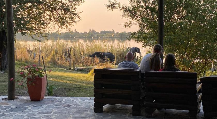 a man and a woman sitting on a bench in a park, Big 5 Toro Lodge in Kasane