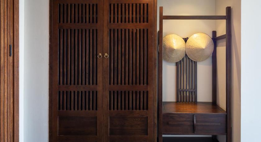 a room with a wooden door and a wooden shelf, Nghê Prana Villa & Spa Hoi An in Hoi An