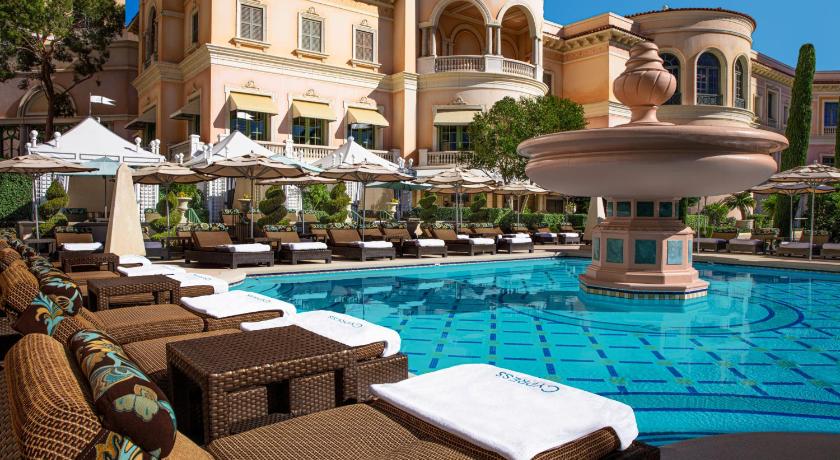 a hotel room with a pool, chairs, and tables, Bellagio Hotel in Las Vegas (NV)