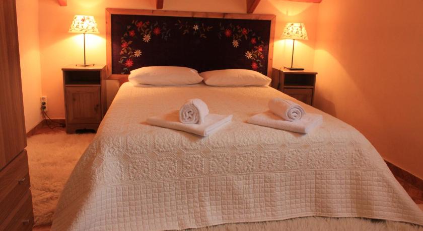a bed with a white blanket and pillows on top of it, Patriko in Arachova
