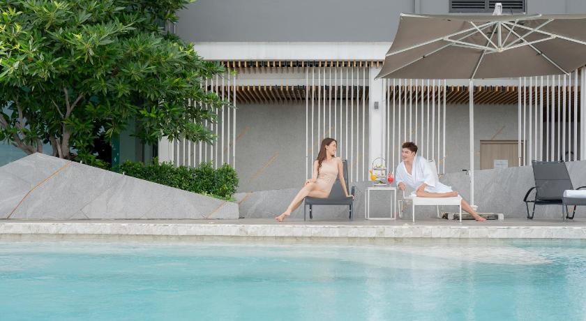 two people lounging on a balcony overlooking a pool, Holiday Inn & Suites Si Racha Laemchabang (SHA Plus+) in Chonburi