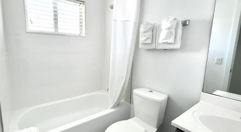 a white toilet sitting next to a bath tub in a bathroom, Beach Gardens in Fort Lauderdale (FL)