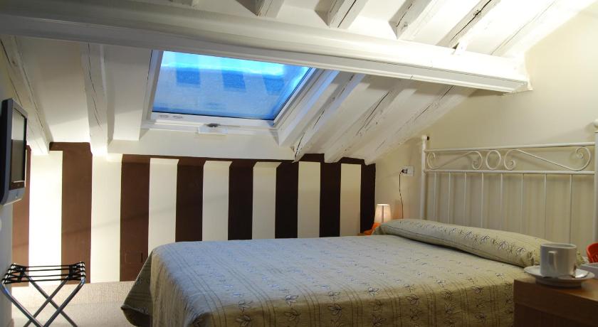 a bedroom with a bed, desk and television, Hotel Il Guercino in Bologna