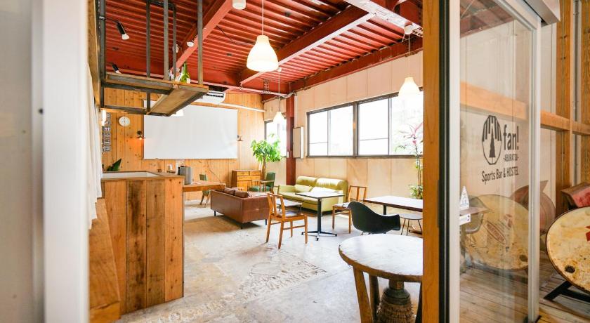 a living room with a wooden floor and a large window, fan! - Aburatsu - Sports Bar & Hostel in Nichinan