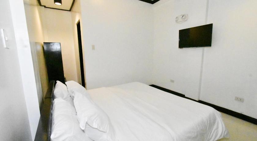 a white bed in a room with a white wall, Swiftlets Inn in Palawan