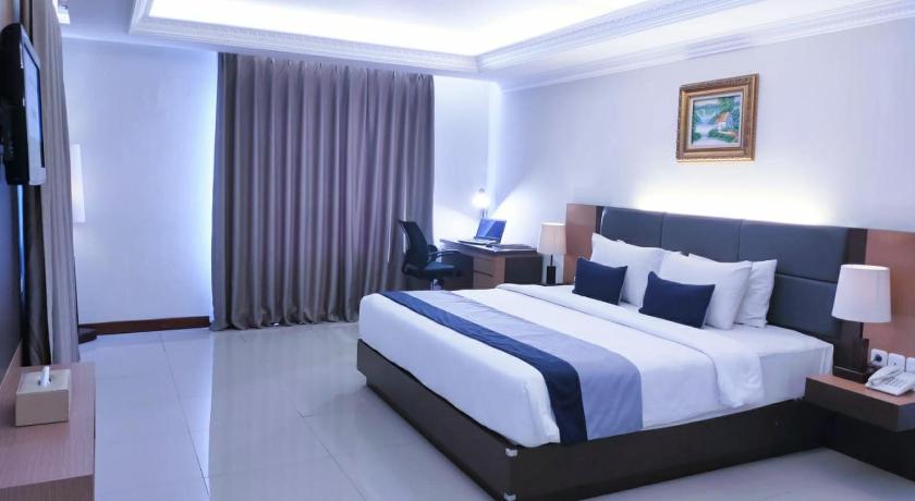 a hotel room with a large bed and a large window, D'Senopati Malioboro Grand Hotel in Yogyakarta