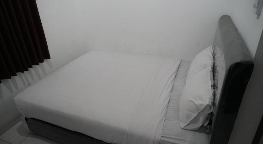 a white bed sitting in a room next to a wall, Casa Feby Guest House in Bandung