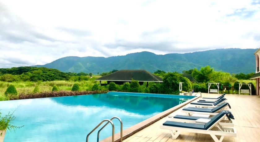 a pool with chairs and tables in front of a large body of water, Aurora Resort Khao Yai in Khao Yai