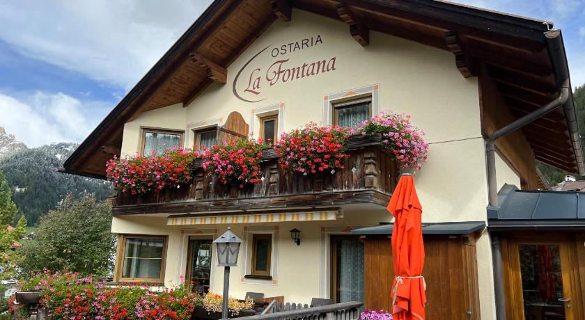 a building with a sign on the front of it, Ostaria La Fontana in Corvara In Badia