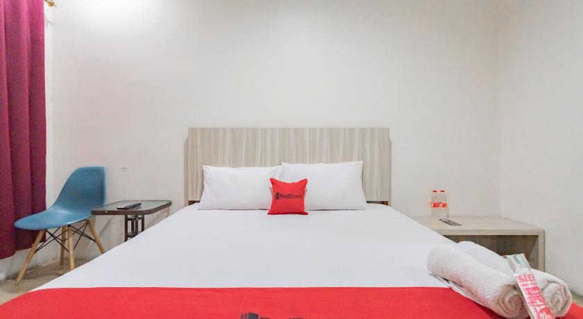 a bed that has a red blanket on it, OYO 1360 Bumi Makhraja Syariah in Bandung