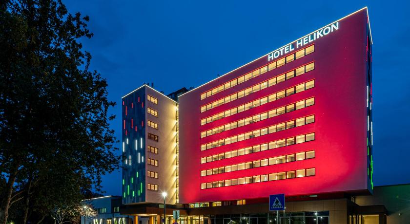 a large building with a neon sign on top of it, Hotel Helikon in Keszthely