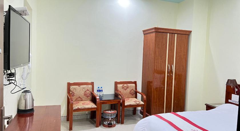 a room with a bed, chair, table and television, Huy Hoang Hotel in Dong Van