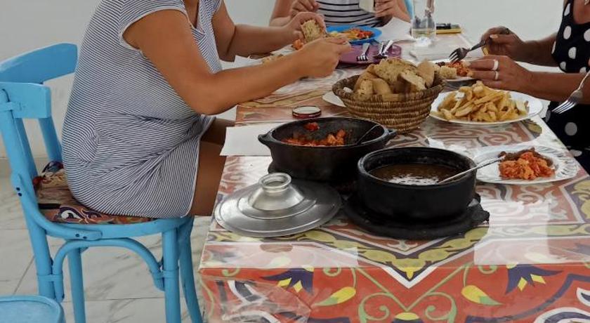 a woman sitting at a table with a plate of food, Nuba Tod Abouda Guest House in Aswan