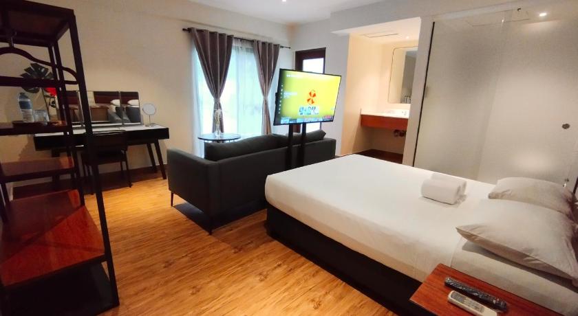 a hotel room with a bed, desk, and a television, The Hub District Garden Suites in Manila