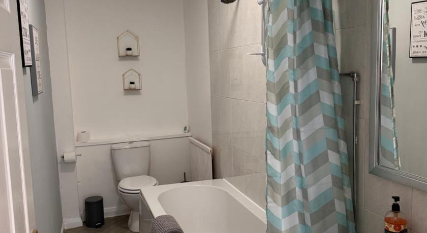 a bath tub sitting next to a toilet in a bathroom, Crown street getaway in Ayr