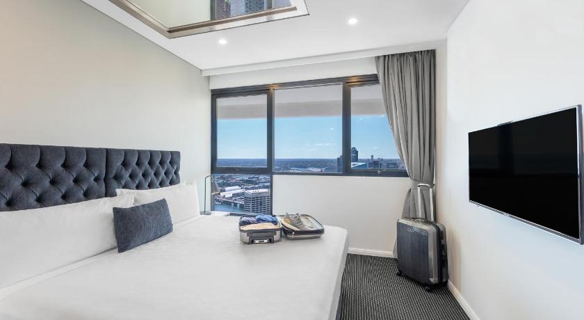 a hotel room with a bed and a television, Meriton Suites Kent Street in Sydney