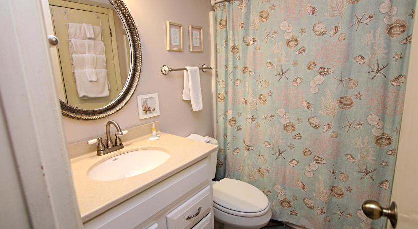 a bathroom with a toilet, sink, and shower curtain, Driftwood Towers 1D condo in Gulf Shores (AL)