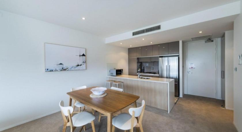 a kitchen with a table, chairs and a refrigerator, Accommodate Canberra - Lakefront in Canberra