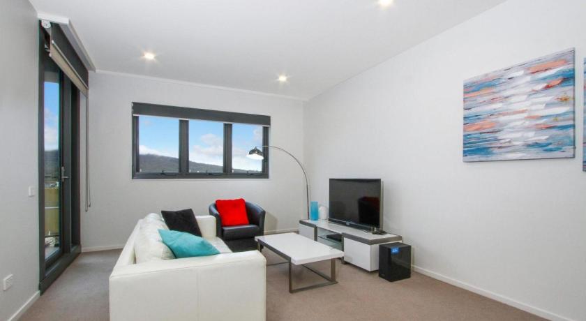 a living room filled with furniture and a tv, Accommodate Canberra - IQ Smart Apartments in Canberra