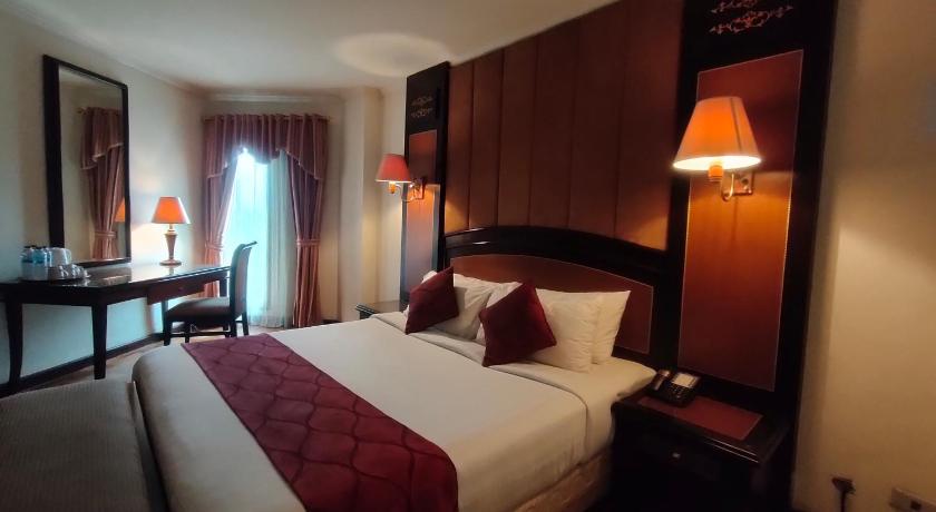 a hotel room with a bed and two lamps, Hotel Kaisar in Jakarta