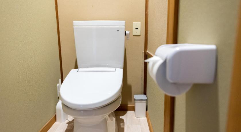 a white toilet sitting in a bathroom next to a wall, AIBIYA in Nagano