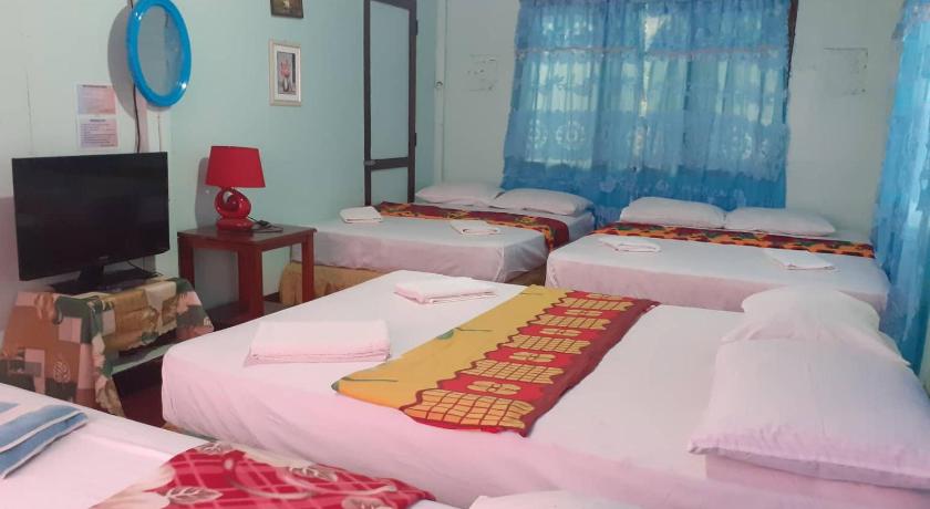 a bed room with two beds and a television, Knights-Apple Inn in Camiguin