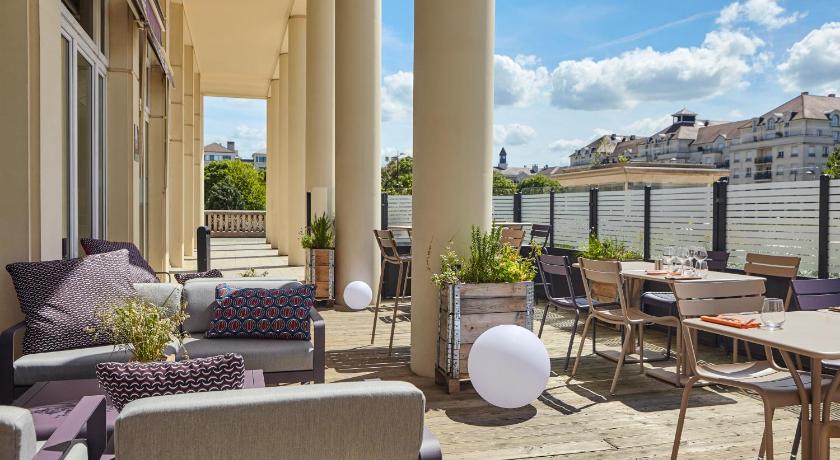 a patio area with chairs, tables and umbrellas, Hotel Mercure Marne la vallee Bussy St Georges in Bussy-Saint-Georges