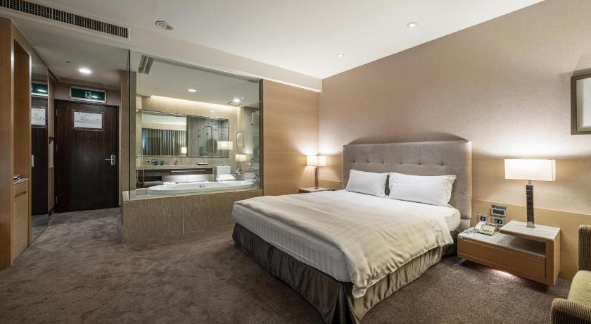 a hotel room with a bed and a dresser, Taipung Suites Hotel in Tainan