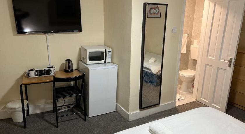 a room with a television and a refrigerator, Stratford Hotel in London