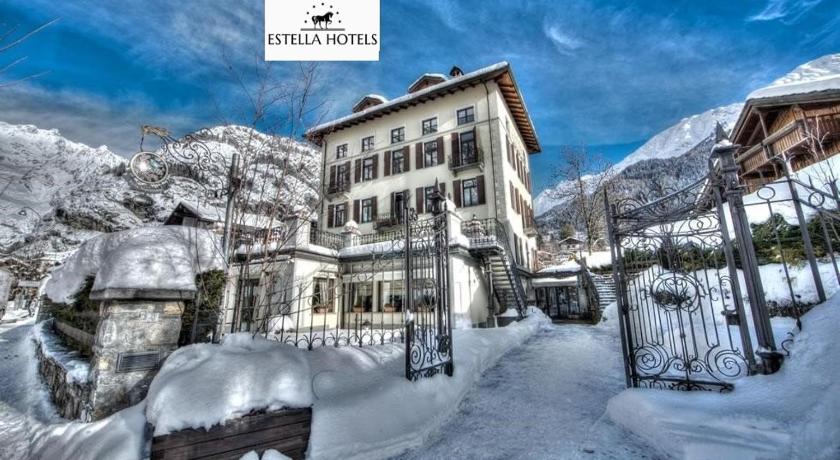 a snowy landscape with a building and snow covered mountains, Villa Novecento Romantic Hotel - Estella Hotels Italia in Courmayeur