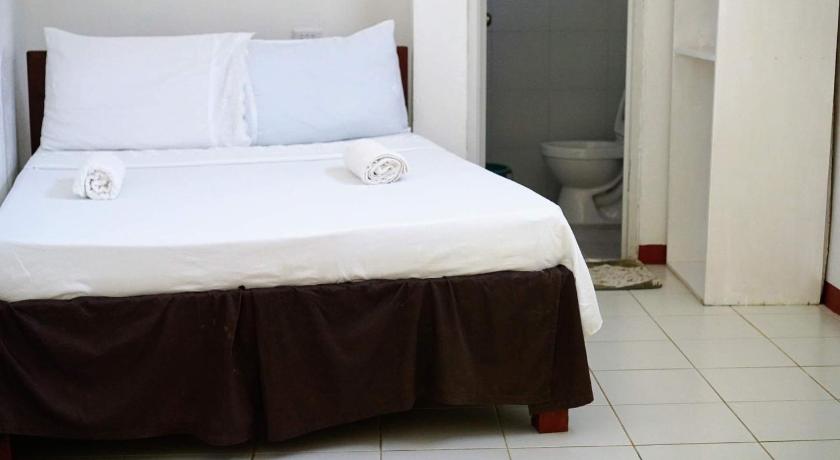 a white bed sitting in a room next to a door, Island Rendevoo Cottages in Siquijor Island
