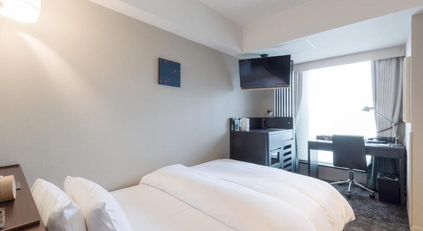 a hotel room with a bed and a television, SHIROYAMA HOTEL kagoshima in Kagoshima