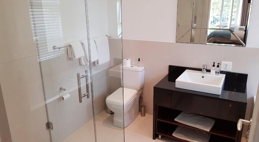 a bathroom with a toilet, sink, and mirror, Q on First Guesthouse in Johannesburg