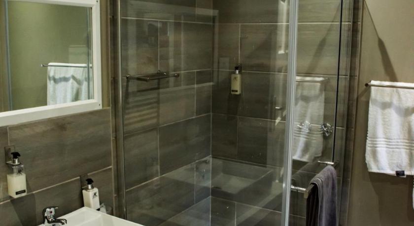 a bathroom with a shower, sink, and mirror, Vanilla Guesthouse in Johannesburg