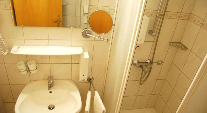 a bathroom with a sink, toilet and mirror, Hotel Baross in Gyor