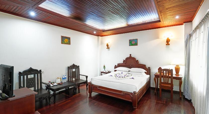 a hotel room with a bed, chair, and nightstand, KMA NAYPYITAW HOTEL in Nay Pyi Taw