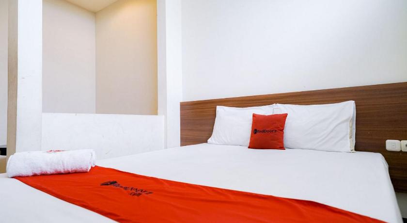 a bed with a white comforter and pillows, RedDoorz near Braga Street in Bandung