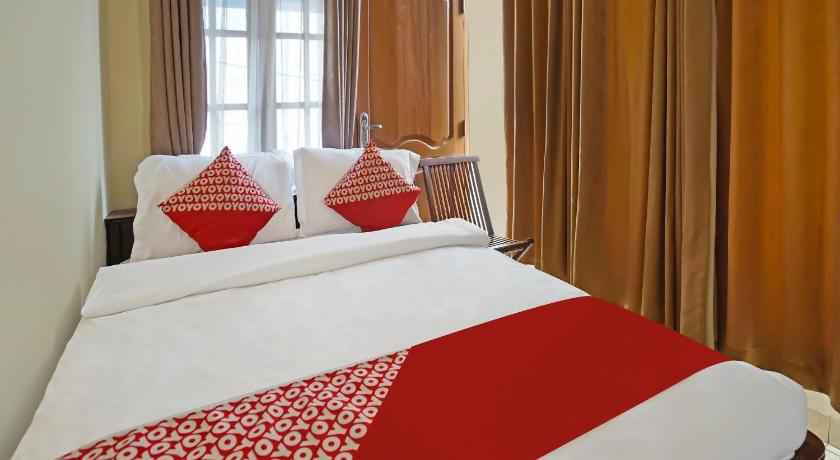 a bed with a white comforter and pillows, OYO 335 Wisma Empat Lima Syariah in Palembang