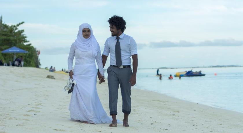 a couple standing on a beach next to a body of water, Beach Palace in Male City and Airport