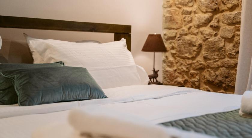 a bed with white sheets and pillows in a room, Afanos Guesthouse in Arachova