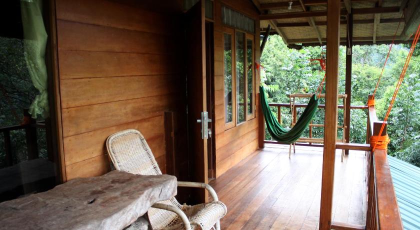 a patio area with a bed, chair, and table, On The Rocks Bungalows, Restaurant and Jungle Trekking Tours in Bukit Lawang