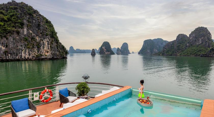 a man is swimming in a pool near a large body of water, Peony Cruise managed by Big Bay Group in Hạ Long