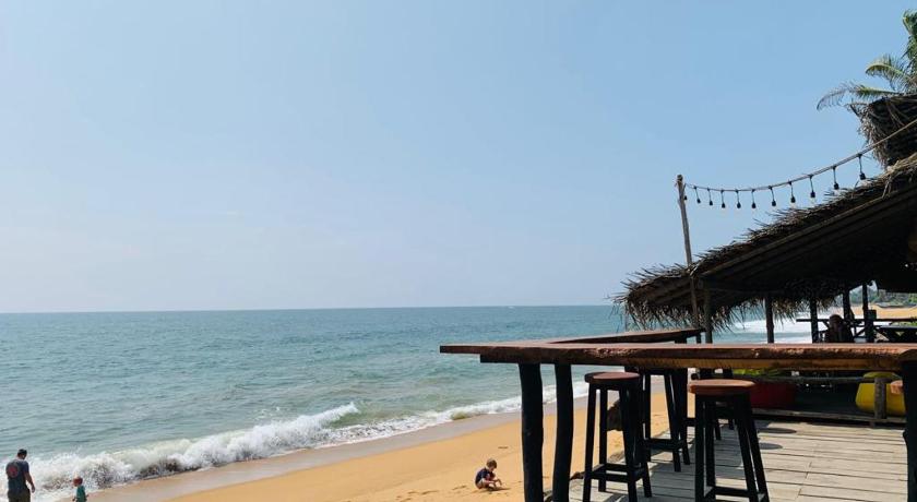 a beach area with chairs, tables and umbrellas, Backpack Beach Hostel & Reggae Bar in Galle